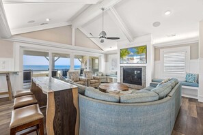 A spacious living area with a large sofa, a fireplace, and a view of the ocean. - Happy Sol *9 bedroom*Oceanfront*Elevator*Pool (Nags Head)