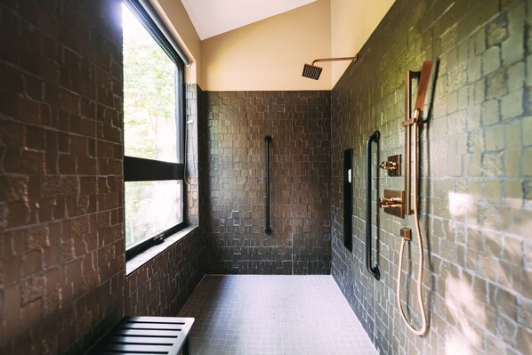 A narrow, tiled bathroom with a window, a towel rack, and a showerhead. - Twelve34 House, Penthouse in the Trees, Luxury Hocking Hills, Trails (Laurelville)
