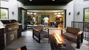An outdoor patio with a grill, seating area, and a fire feature.