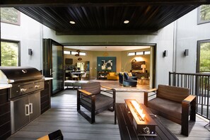 An outdoor patio with a grill, seating area, and a view into the house. - Twelve34 House+ Penthouse in the Trees + Wall of Glass + Hot Tub (Laurelville)