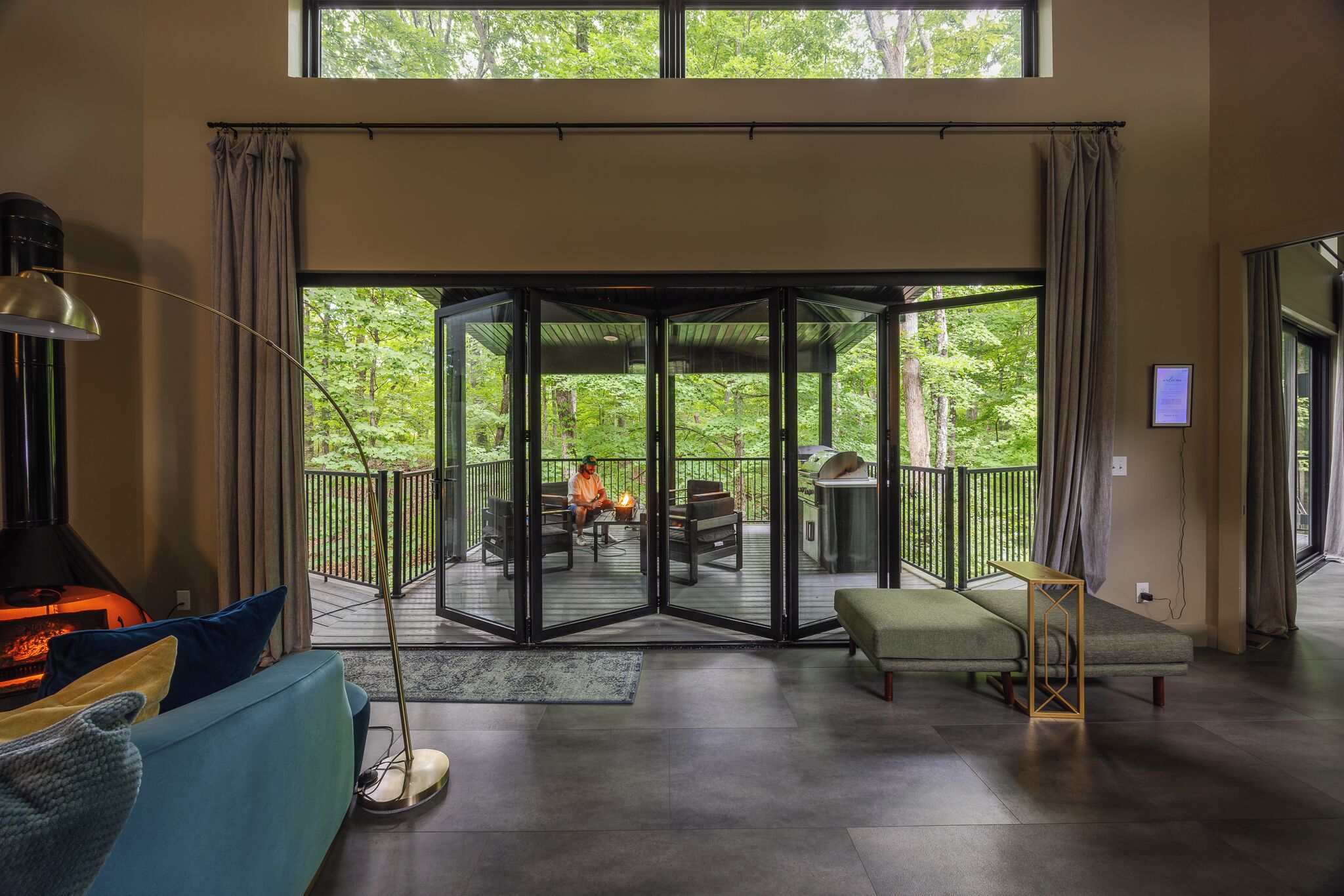 Una sala de estar moderna con chimenea, zona de estar y puerta de vidrio que da a una terraza exterior.