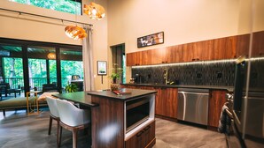 A modern kitchen with a wooden island, stainless steel appliances, and a view of the outdoors.