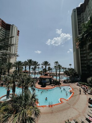 Un espace piscine d’un complexe hôtelier comprenant plusieurs piscines, des palmiers et un décor de plage.