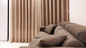 Ein modernes Wohnzimmer mit einem beigen Sofa und passenden Vorhängen.
