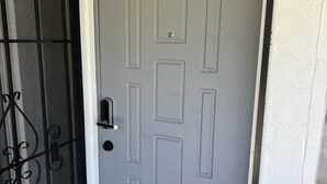 Una porta grigia con una grata di sicurezza metallica e stipite bianco.