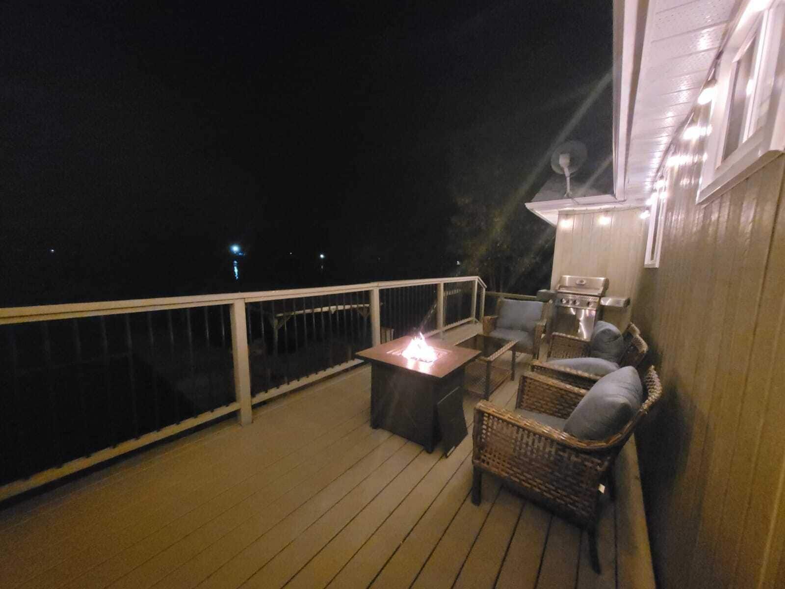 A deck with a table and chairs, a grill, and a railing.