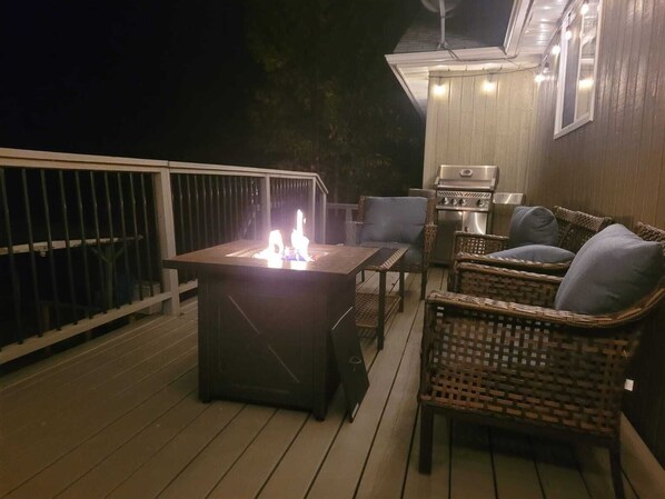 An outdoor deck with a grill and a table with a fire feature.