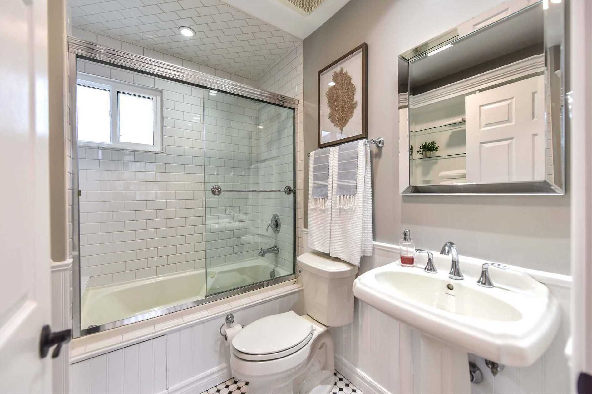 Een badkamer met een douchecabine, toilet en een wastafel met spiegel erboven.