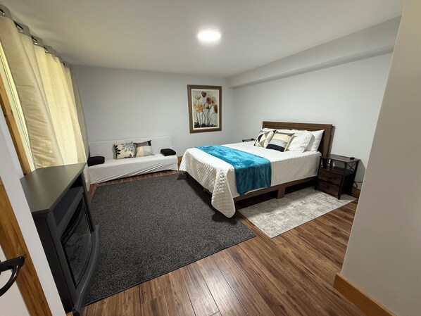Ein Schlafzimmer mit Bett, einer Couch, einem Fernseher und einem Bild an der Wand.