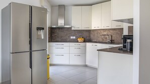 A modern kitchen with a stainless steel refrigerator, white cabinets, a dark backsplash, and a coffee machine. - Superb 3P in a quiet location Swimming pool Terrace Barbecue Pétanque aircon (ANTIBES)