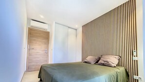 A modern bedroom with a bed, a wooden slat wall, and an air conditioning unit. - New T2 apartment for 4 people in residence with swimming pool (SAINTE MAXIME)