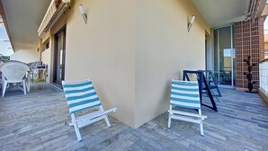 A balcony with two striped lounge chairs, a table, and chairs. - New T2 apartment for 4 people in residence with swimming pool (SAINTE MAXIME)