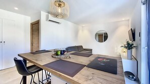 A modern dining area with a wooden table, black chairs, and a unique pendant light. - New T2 apartment for 4 people in residence with swimming pool (SAINTE MAXIME)