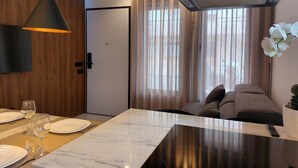 Moderni hotellihuone, jossa on ruokailutila, sohva ja televisio.