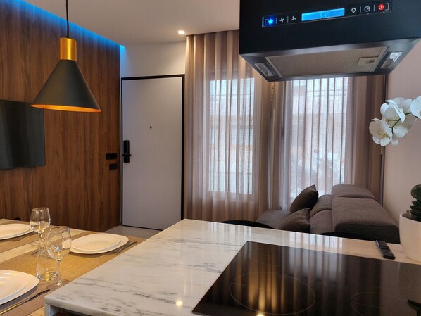 A modern hotel room with a dining area, a sofa, and a TV.