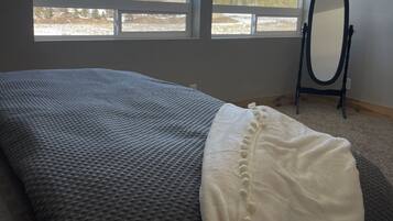 A bedroom with a large bed, a mirror, and a view of a mountain.