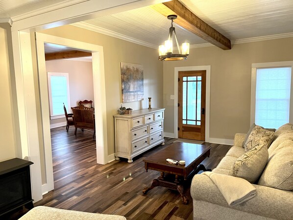A spacious living room with hardwood floors, a wooden coffee table, a sofa, and a chandelier.