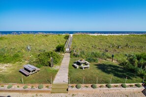 Un sendero que conduce a una playa con una mesa de picnic y bancos.