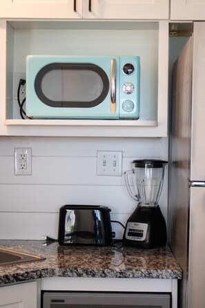 A kitchen with a teal microwave, a toaster, and a blender on the counter.