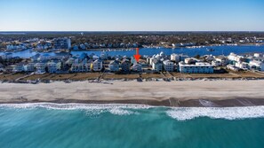 Vista aérea de una zona residencial costera con propiedades frente al mar, un puerto deportivo y cielo despejado.