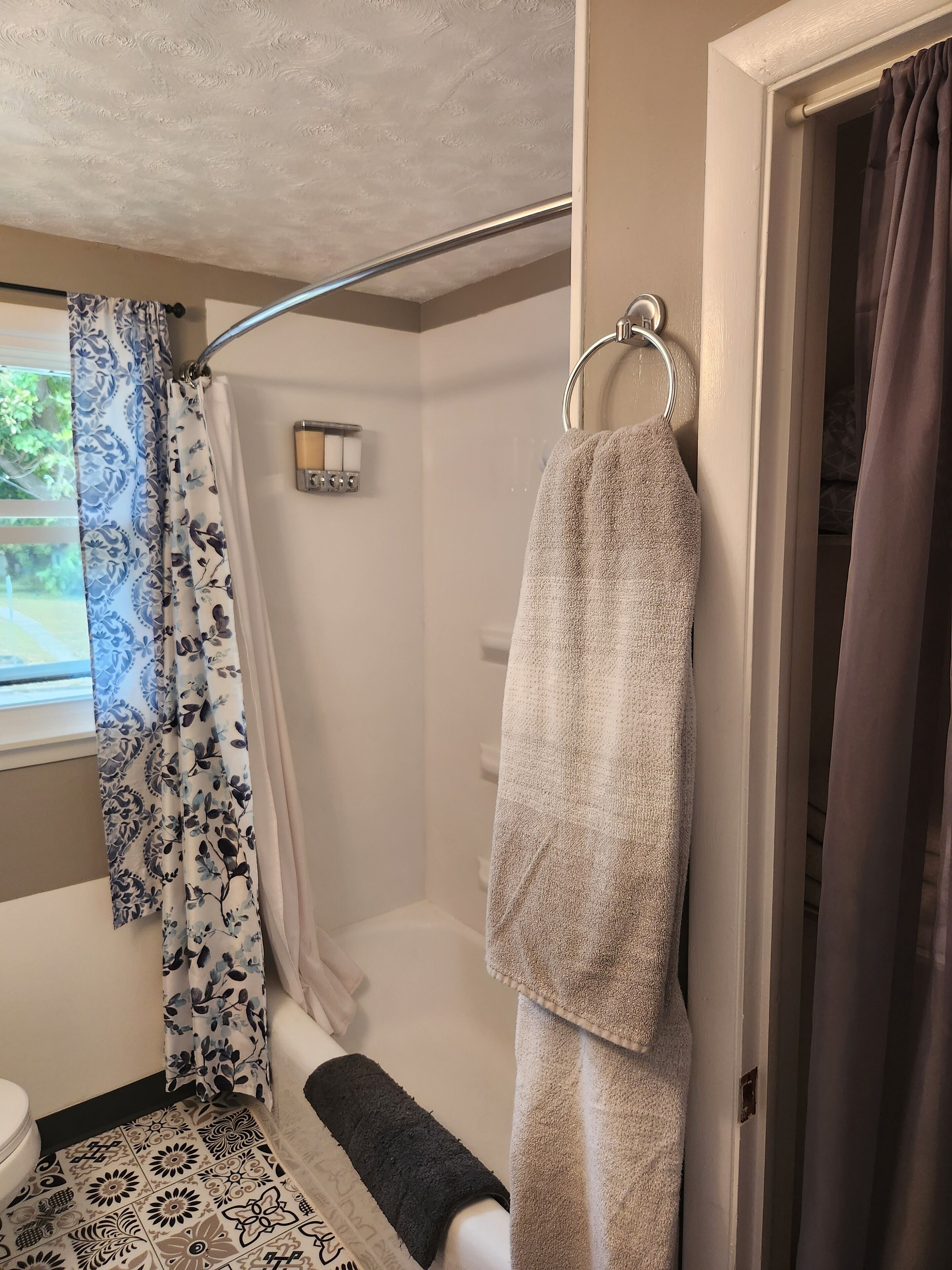 A bathroom with a shower, toilet, and a towel rack.