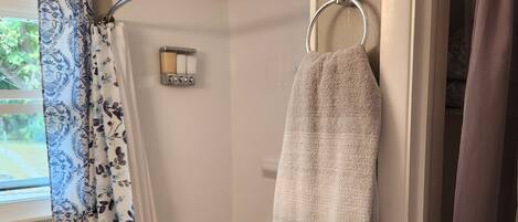 A bathroom with a shower, toilet, and a towel rack.