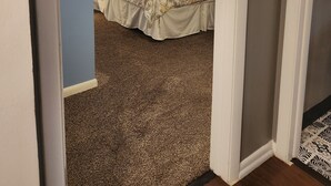 A bedroom with a bed, a ceiling fan, and a window with curtains.