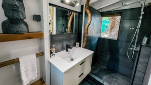 A modern bathroom with a white vanity, a large mirror, a black shower enclosure, and a wooden shelf with a towel. - Mango Cottage Orient Bay, Charming and Authentic (Collectivité de Saint-Martin)