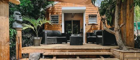 A wooden house with a covered patio, outdoor seating, and a stone statue.