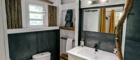 A modern bathroom with a toilet, sink, and mirror.