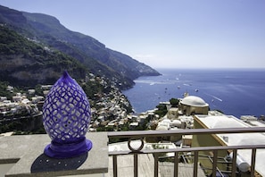 Eine Küstenstadt mit einem auffälligen, violetten dekorativen Gegenstand auf einem Balkon mit Blick aufs Meer.
