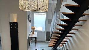 Um interior moderno com uma escada, uma área de refeições com cadeiras e um lustre.