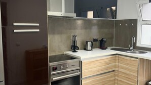 Uma cozinha moderna com geladeira de aço inoxidável, forno embutido, micro-ondas e pia.