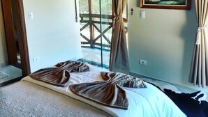 A bedroom with a bed, a painting, and curtains.