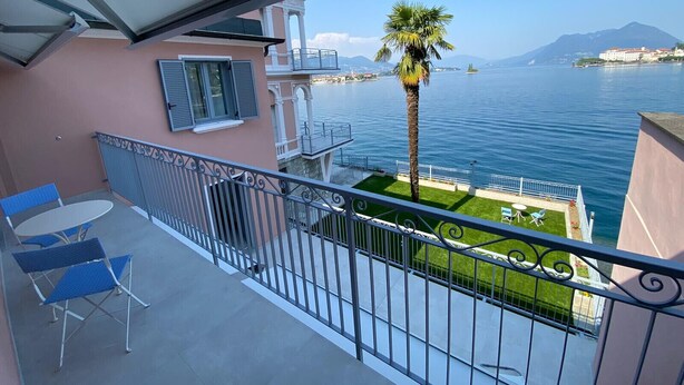 Un balcon avec vue sur un lac, un palmier et une montagne au loin.