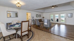 A spacious living area with a dining table, chairs, a sofa, and a ceiling fan.
