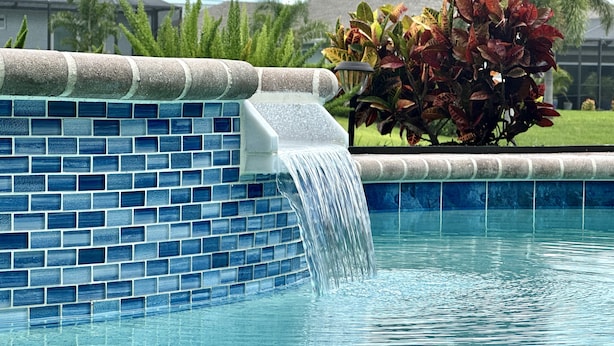 A swimming pool with a blue-tiled edge and a waterfall feature. - * Waterfront home to relax, reconnect, and create unforgettable memories together! * (Rotonda West)