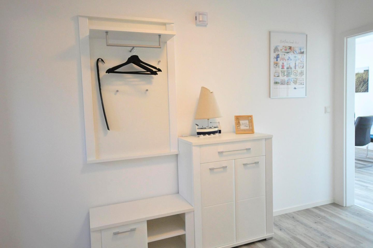 A minimalist room with a white wardrobe, a coat rack, and a framed picture on the wall.