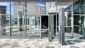 Ein moderner Gebäudeeingang mit Glastüren und Fliesenboden.