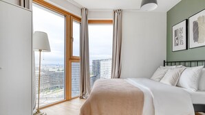 Ein Schlafzimmer mit großem Fenster, einem Bett, einer Lampe und Kunstwerken an der Wand.