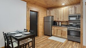 Una cocina compacta con gabinetes de madera, un refrigerador, un microondas y una estufa.