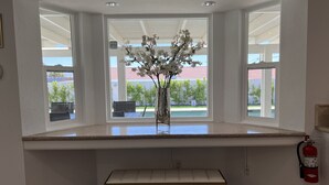Eine Küche mit einem großen Fenster, einer Blumenvase, einer Bank und einem Feuerlöscher.