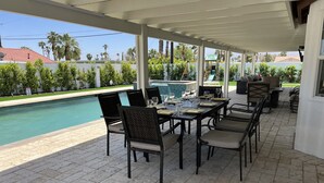 Eine Terrasse im Freien mit Pool, überdachter Sitzgelegenheit und Blick auf Pool und Grünflächen.