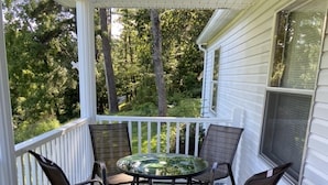 A covered porch with a round table and four chairs.