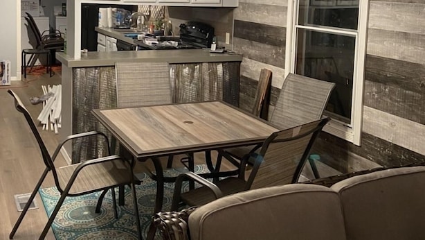A compact kitchen with white cabinets, a central island, and a dining area with a wooden table and chairs.