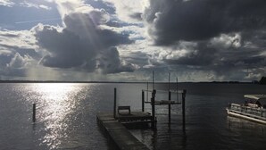 A dock extending into calm water with a boat moored at the end.