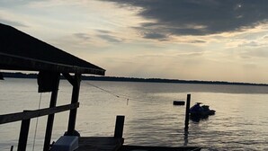A dock with a boat and a jet ski, a wooden pier, and a cloudy sky over a body of water.