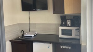 Cozinha compacta equipada com televisão integrada, micro-ondas, cafeteira e mini-geladeira.