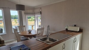 Una cocina moderna con encimera de madera, armarios blancos y un fregadero empotrado, además de un comedor con mesa y sillas.