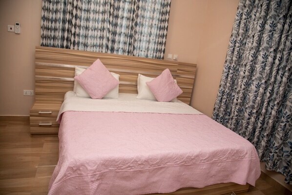 A bedroom with a wooden headboard, a pink bedspread, and matching pillows.